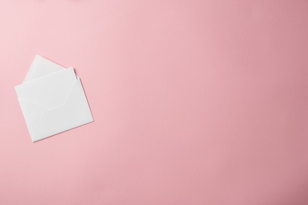 top view of white envelope with blank greeting card isolated on pink backgroundの写真素材