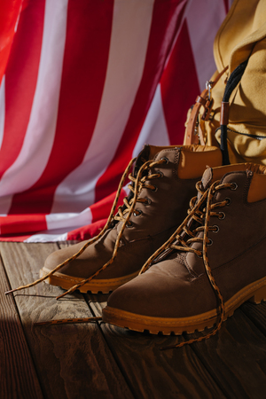 close-up view of trekking boots, backpack and american flag on wooden surfaceの写真素材