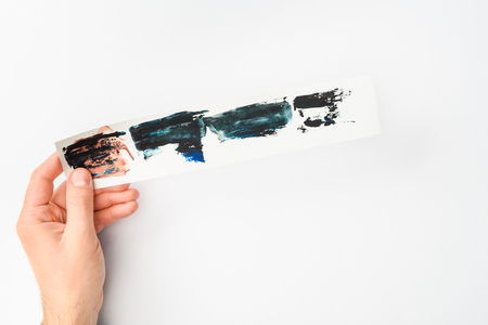Man holding paper with abstract watercolor brushstrokes set on white backgroundの写真素材