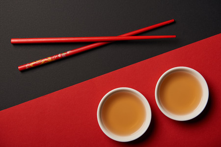top view of chopsticks with traditional chinese tea on red and black backgroundの写真素材