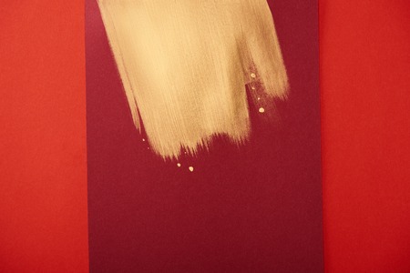 abstract burgundy background with golden brushstroke isolated on redの写真素材