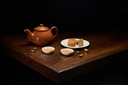 tea pot, mooncakes and cups on wooden table isolated on blackの写真素材