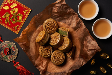top view of traditional mooncakes with chinese talismans and tea isolated on blackの写真素材