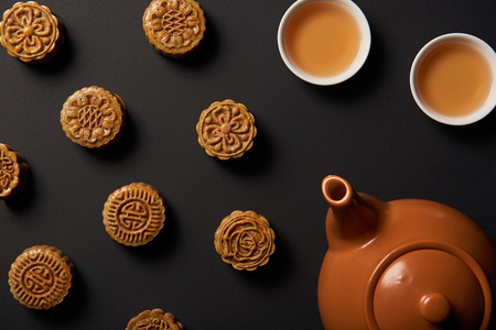 Top view of mooncakes, tea pot and cups isolated on blackの写真素材