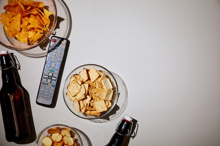 top view of bottles near remote control and snacks on white backgroundの写真素材