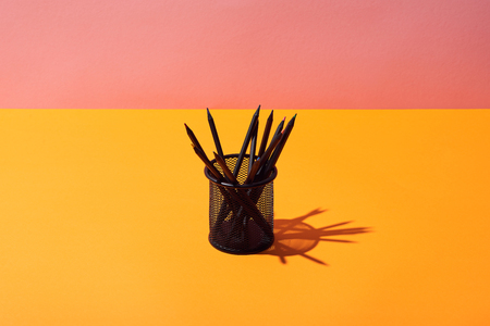 pencil holder with pencils on yellow surface and pink backgroundの写真素材