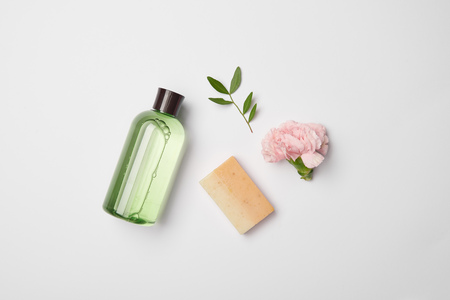 Top view of different cosmetic bottles, soap, tea plant branch and carnation flower on white backgroundの写真素材