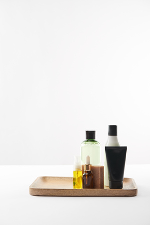 Wooden tray with various cosmetic containers and soap on white surfaceの写真素材