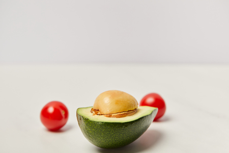 selective focus of cut avocado and cherry tomatoes on grey backgroundの写真素材