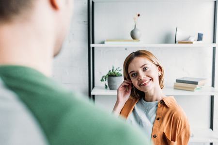 smiling young woman looking at friend and holding hand near headの写真素材