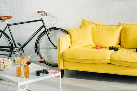 living with comfortable yellow sofa and table with drinks and snacksの写真素材