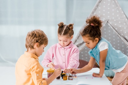 cute multiethnic children sitting and drawing together