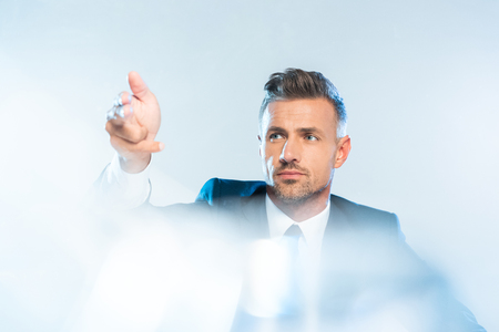 handsome adult businessman in suit touching something isolated on white, artificial intelligence conceptの写真素材