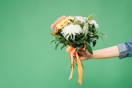cropped view of woman holding flower bouquet isolated on green