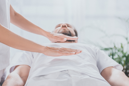cropped shot of bearded man receiving reiki healing session above stomachの写真素材