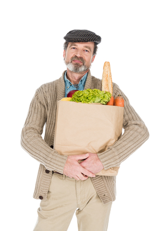 cheerful senior man holding paper bag with groceries isolated on whiteの写真素材