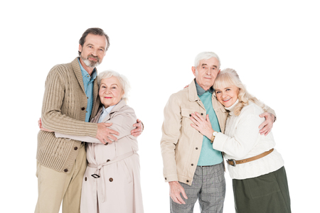 cheerful retired couples hugging and smiling isolated on whiteの写真素材