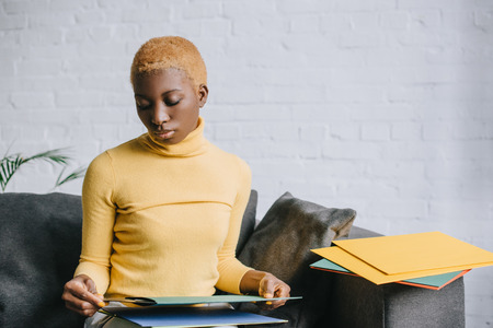 dreamy african american woman sitting on sofa with vinyl recordsの写真素材