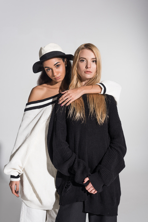 beautiful african american woman hugging caucasian friend and they looking at camera on whiteの写真素材