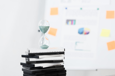 hourglass on stack of DVDs in light business office