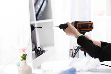 cropped image of businesswoman going to drill computer with electric drill in officeの写真素材
