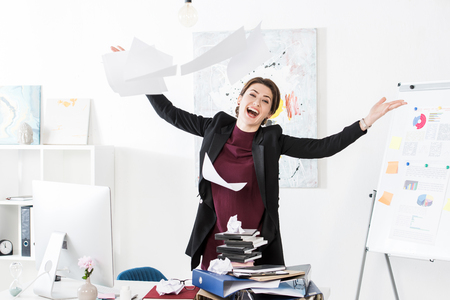 happy attractive businesswoman throwing up documents in officeの写真素材
