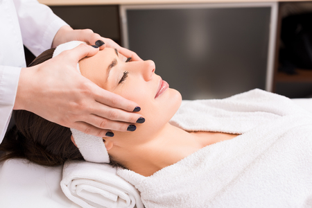 cosmetologist giving manual face massage to woman at beauty salonの写真素材