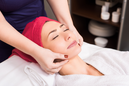 beautician doing manual face massage to woman at beauty salonの写真素材
