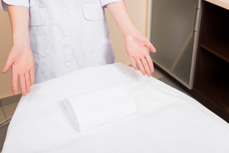 cropped view of cosmetologist standing and pointing with hands at massage table at beauty salonの写真素材