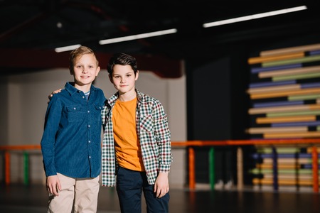 Selective focus of smiling boy hugging friend by shoulderの写真素材