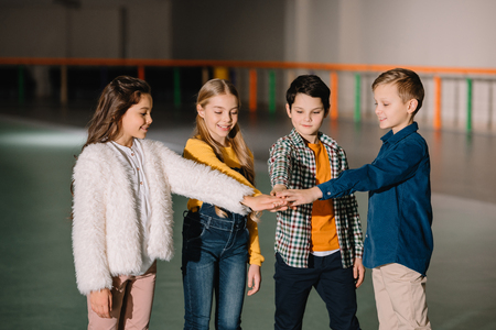 Selective focus of pretty smiling children stretching hands together