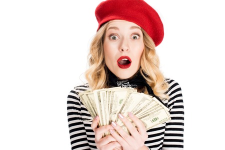 surprised blonde woman holding dollar banknotes in hands isolated on whiteの写真素材