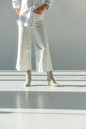 cropped image of woman in fashionable trousers and shoes standing on whiteの写真素材