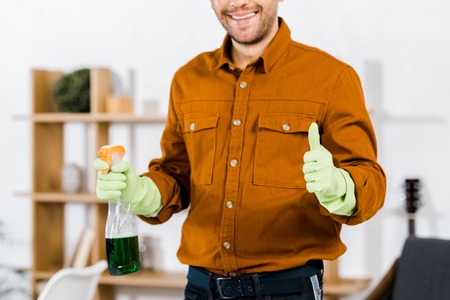 cropped view of man smiling in modern living room doing thumb up gesture and holding bottleの写真素材