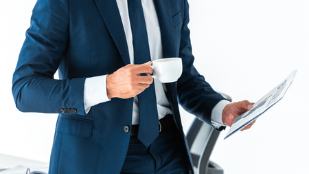 cropped image of businessman holding cup of coffee and newspaper isolated on whiteの写真素材