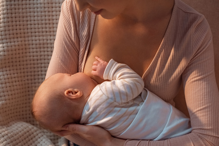 cropped shot of young mother breastfeeding baby at nightの写真素材