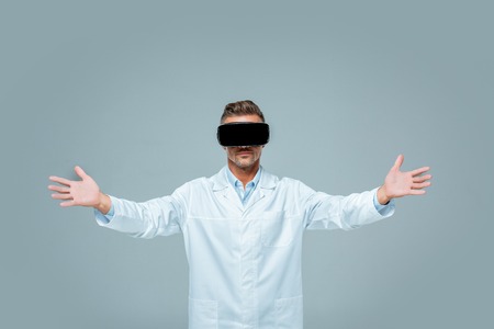 scientist in virtual reality headset holding something in open arms isolated on grey, artificial...