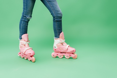 partial view of child wearing denim and pink rollerblades isolated on greenの写真素材