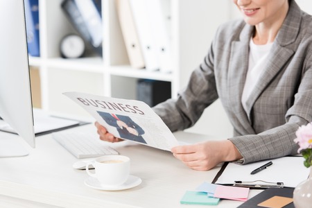 cropped image of businesswoman reading newspaper in officeの写真素材