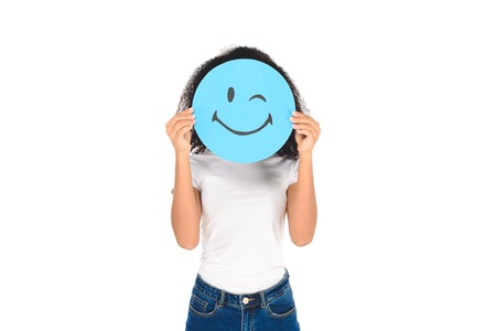 african american girl holding round, blue sign with winking face expression isolated on whiteの写真素材
