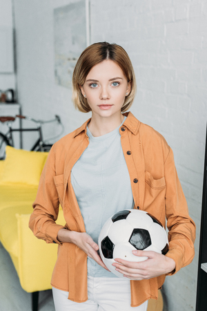 beautiful young woman in orange shirt holding soccer ballの写真素材