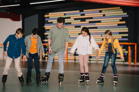Young trainer showing skating basic technics to attentive childrenの写真素材