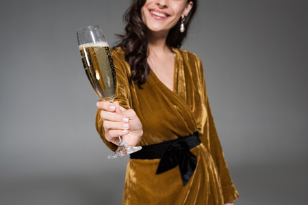 cropped view of smiling woman holding glass of champagne isolated on greyの写真素材