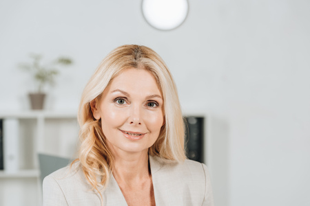 portrait of beautiful blonde mature businesswoman smiling at camera in office