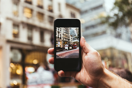 cropped shot fo man with smartphone taking picture of new york city street