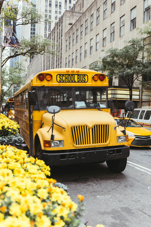 urban scene of yellow school bus and cars on street in new york, usa