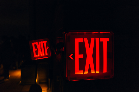 close up view of red exit sign on black backdropの写真素材