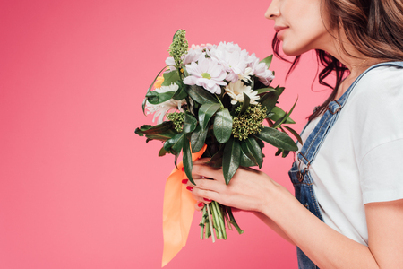 cropped view of woman holding flower bouquet isolated on pinkの写真素材