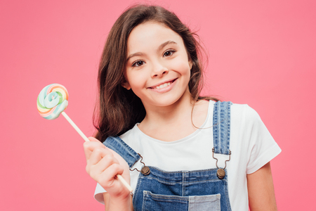 smiling kid holding lollipop isolated on pinkの写真素材