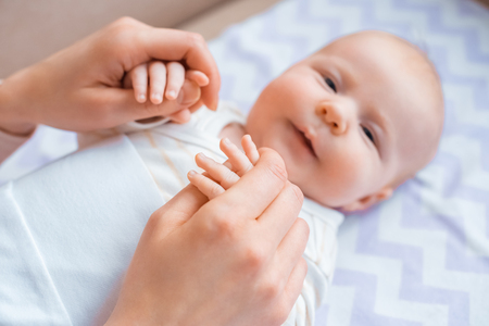 cropped shot of mother holding hands of adorable infant baby looking at cameraの写真素材